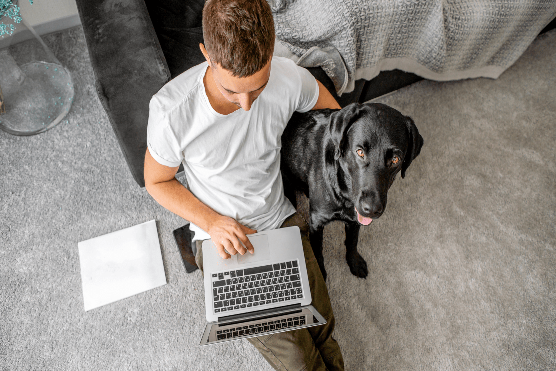 a person sitting on the floor with a laptop and a dog